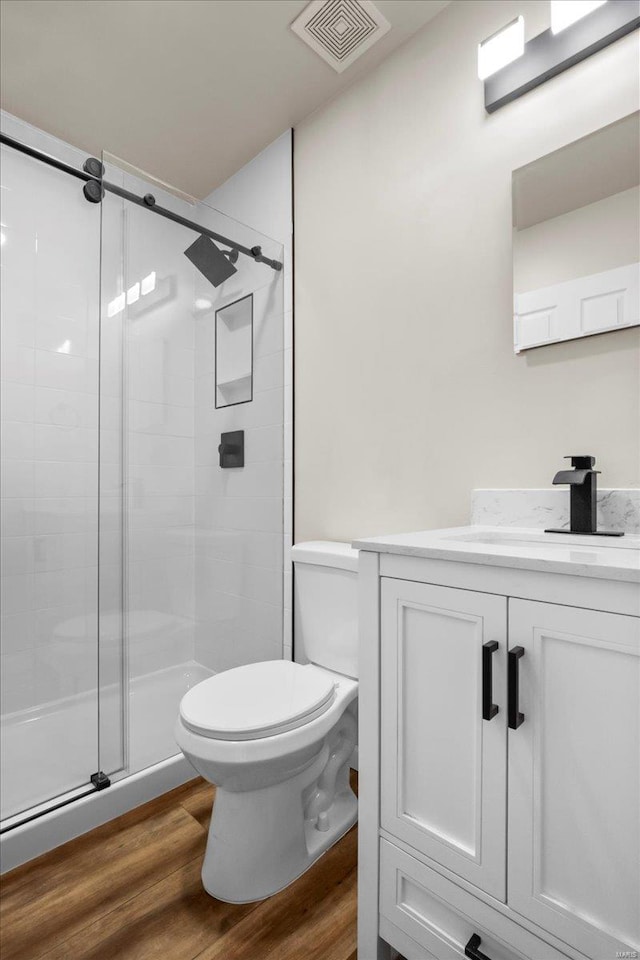 full bath featuring visible vents, toilet, wood finished floors, vanity, and a shower stall