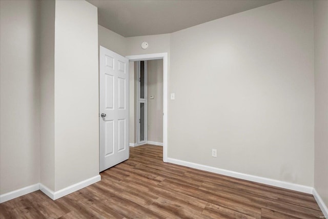 spare room featuring baseboards and wood finished floors