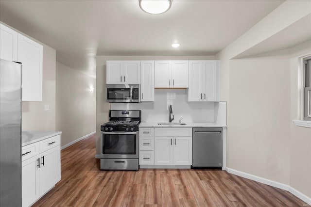 kitchen with light wood-style flooring, stainless steel appliances, a sink, white cabinets, and light countertops