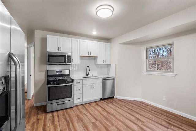 kitchen with light wood finished floors, light countertops, appliances with stainless steel finishes, and a sink