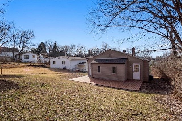 back of house with a chimney, a yard, a deck, and fence