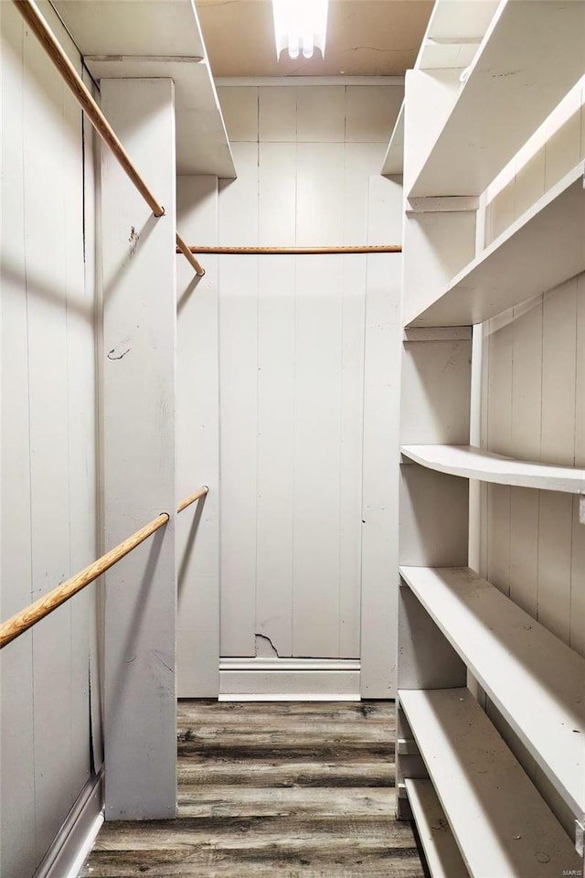 walk in closet with dark wood-style flooring