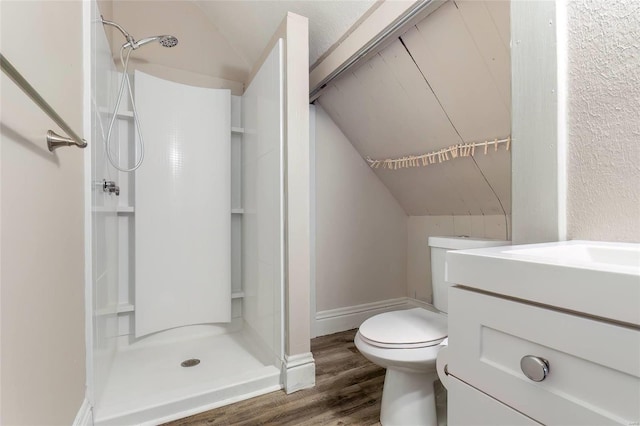 bathroom featuring lofted ceiling, toilet, wood finished floors, vanity, and a shower stall