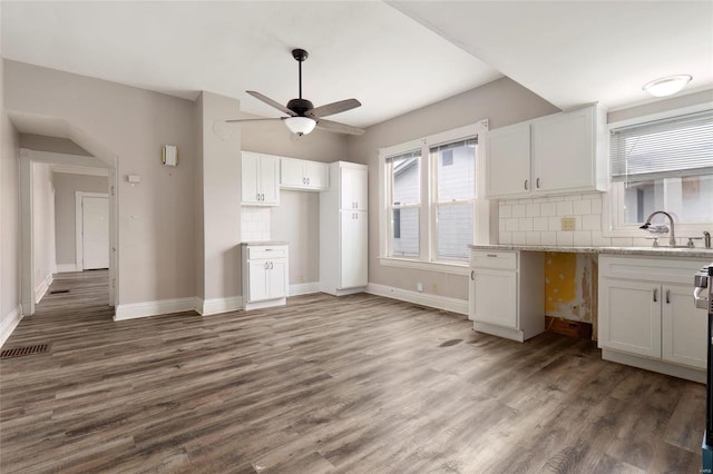 kitchen featuring wood finished floors, backsplash, a sink, and white cabinetry