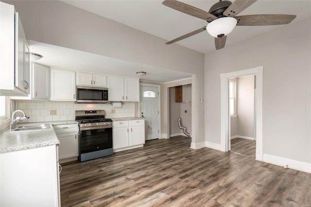 kitchen with dark wood-style flooring, stainless steel appliances, light countertops, backsplash, and a sink