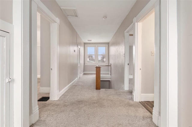 corridor with carpet floors, an upstairs landing, visible vents, and baseboards