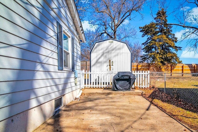 view of patio with an outbuilding, a storage unit, fence, and a grill