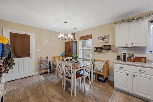 dining space with an inviting chandelier, light wood-style flooring, and baseboards