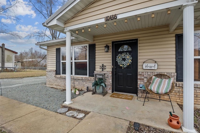 view of exterior entry with covered porch and brick siding