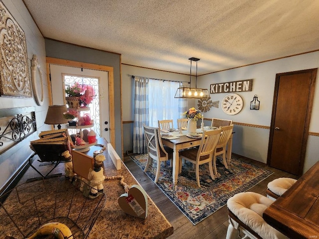 dining space with a textured ceiling, wood finished floors, and crown molding