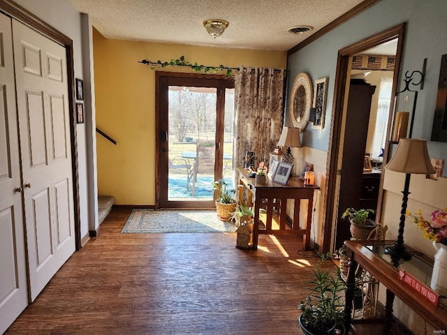 doorway to outside featuring a textured ceiling, stairway, wood finished floors, and visible vents