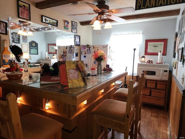 bar with white microwave, wood finished floors, and a ceiling fan