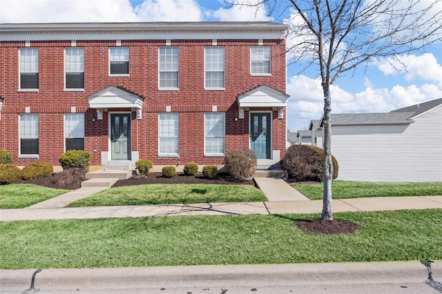 multi unit property featuring brick siding and a front yard