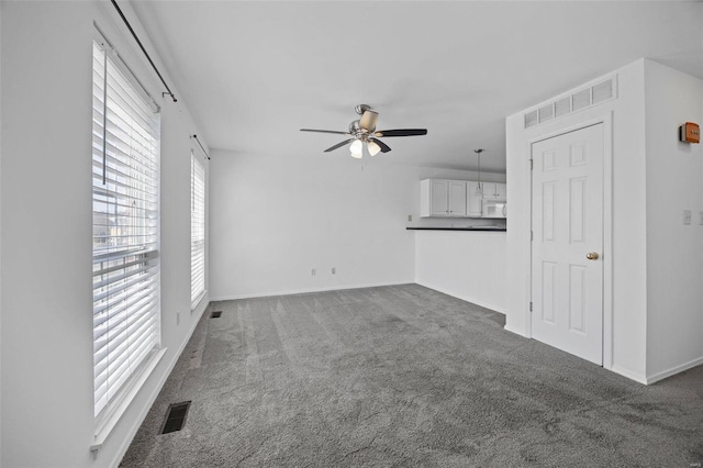 unfurnished living room featuring ceiling fan, carpet flooring, visible vents, and baseboards