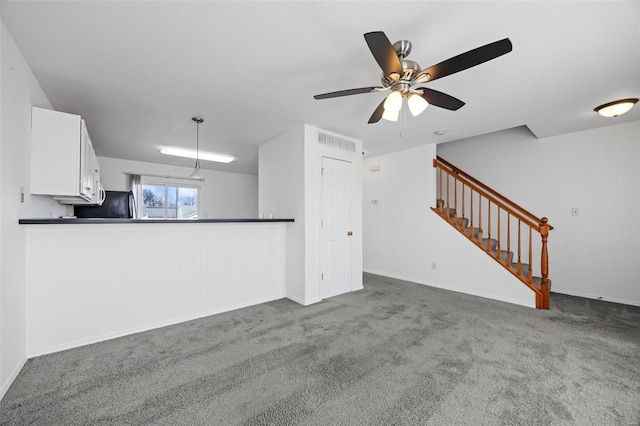 unfurnished living room featuring a ceiling fan, visible vents, baseboards, stairway, and carpet