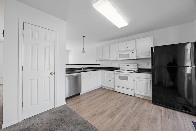 kitchen with dark countertops, white appliances, white cabinets, and a sink