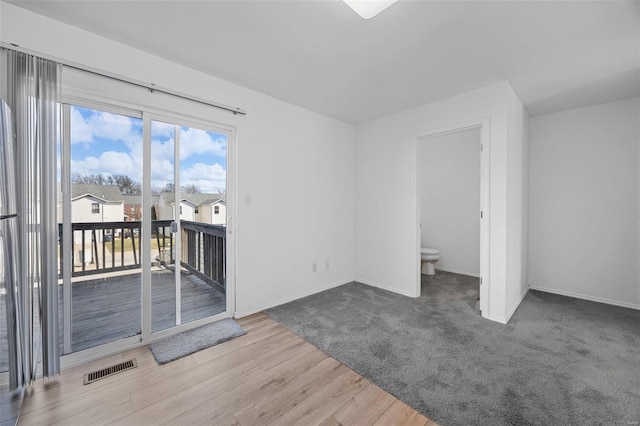 spare room featuring baseboards, visible vents, and wood finished floors