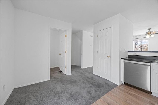 interior space featuring wood finished floors, a ceiling fan, baseboards, dishwasher, and dark countertops