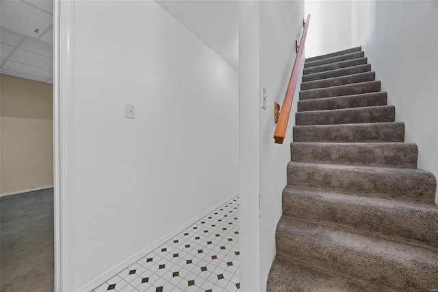 staircase with a paneled ceiling and baseboards