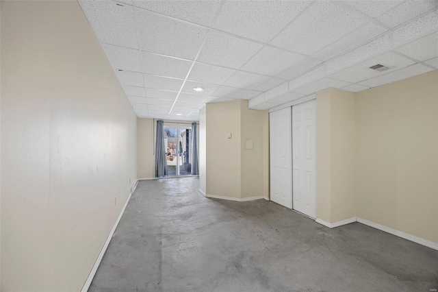 interior space with a paneled ceiling, visible vents, unfinished concrete flooring, and baseboards