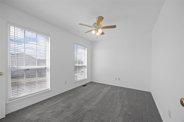 unfurnished room featuring visible vents, baseboards, dark colored carpet, and a ceiling fan