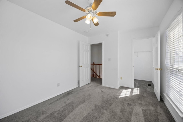 unfurnished bedroom featuring carpet flooring, a ceiling fan, baseboards, a spacious closet, and a closet