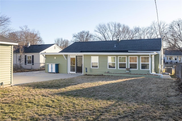 rear view of property featuring roof with shingles, a lawn, central AC unit, a patio area, and fence