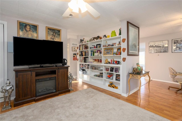 living room with wood finished floors, a ceiling fan, and baseboards