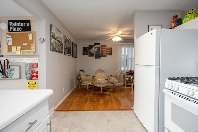 kitchen featuring white range with gas stovetop, baseboards, ceiling fan, light wood-style flooring, and light countertops