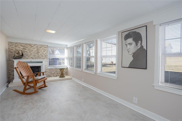 living area with plenty of natural light, a fireplace, baseboards, and crown molding