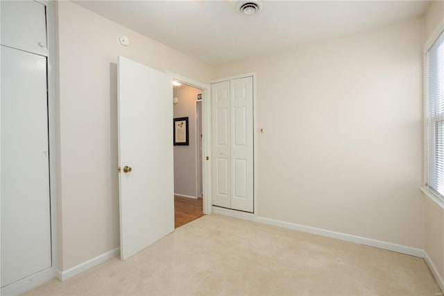 unfurnished bedroom featuring carpet floors, visible vents, and baseboards