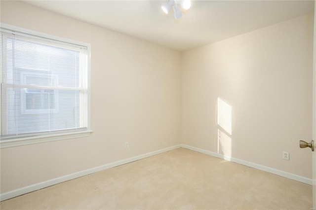 spare room with baseboards and light colored carpet