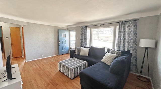 living area with a textured wall, wood finished floors, and baseboards