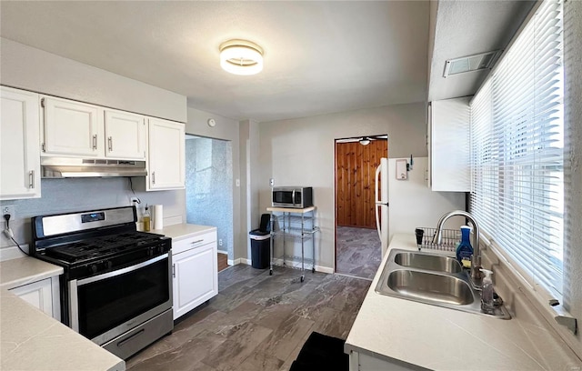 kitchen featuring under cabinet range hood, appliances with stainless steel finishes, white cabinets, and a sink