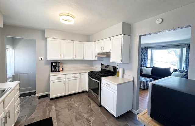 kitchen featuring light countertops, stainless steel range with gas cooktop, white cabinets, and under cabinet range hood