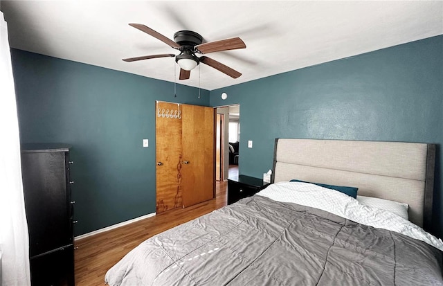 bedroom featuring wood finished floors, a ceiling fan, and baseboards