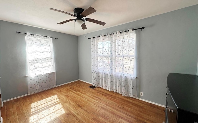 unfurnished room with ceiling fan, wood finished floors, and baseboards