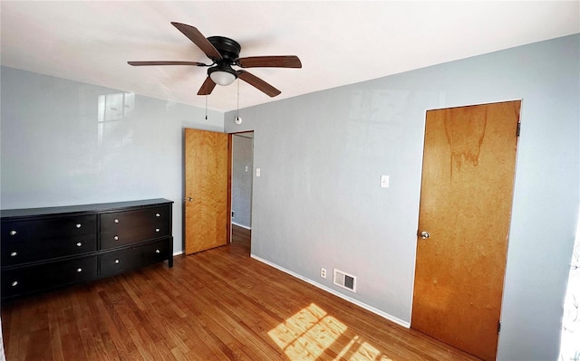 unfurnished bedroom featuring ceiling fan, wood finished floors, visible vents, and baseboards