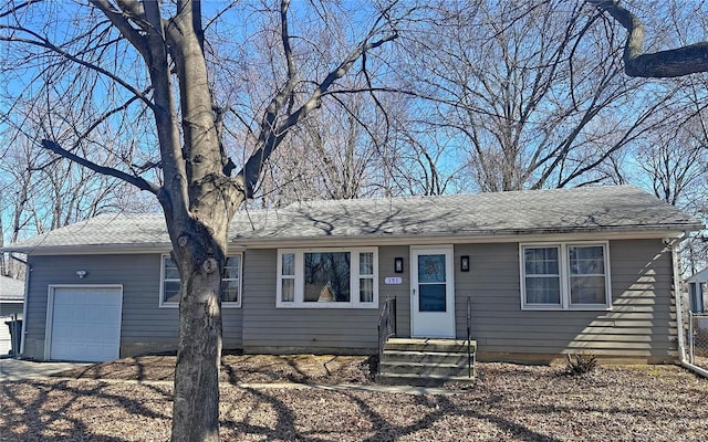 ranch-style home featuring an attached garage, a shingled roof, and entry steps