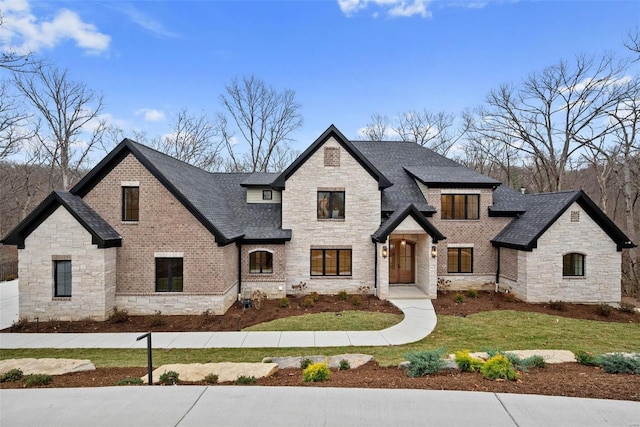 view of front of house featuring a shingled roof, a front lawn, and brick siding