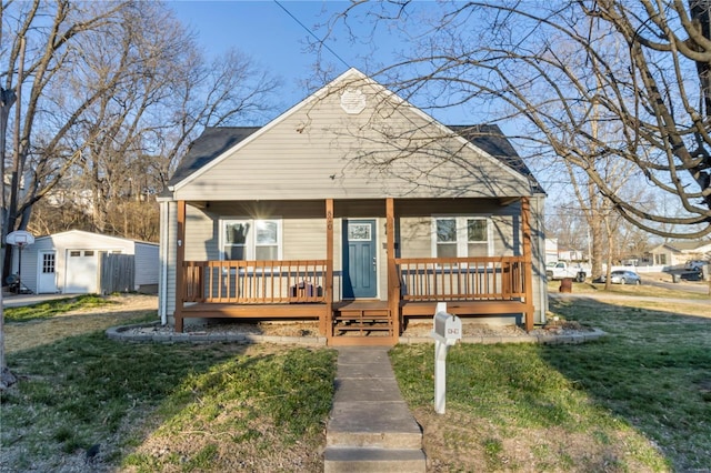 bungalow-style house with a porch, an outdoor structure, and a front lawn