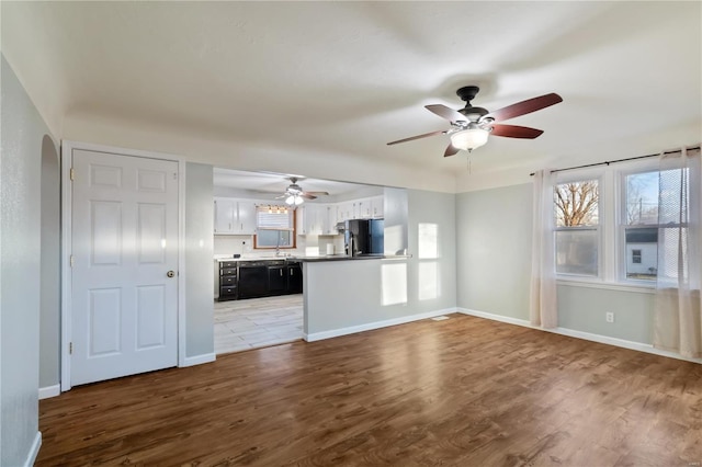 unfurnished living room with baseboards, arched walkways, and wood finished floors