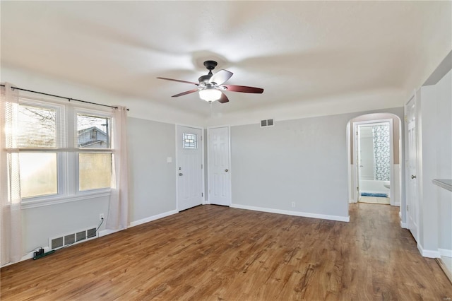 interior space featuring visible vents, arched walkways, baseboards, and wood finished floors