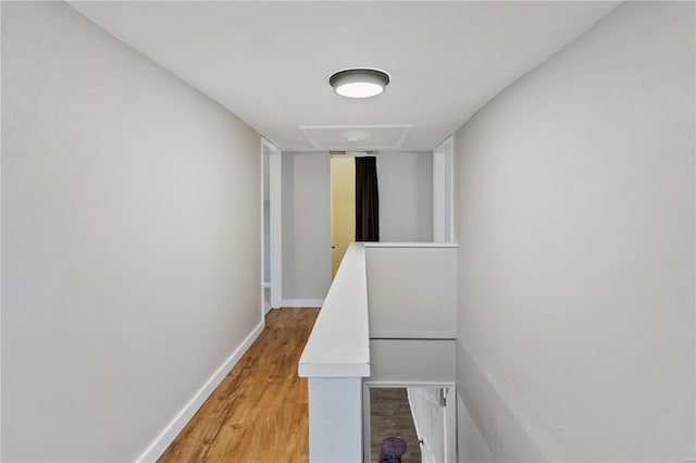 hall featuring an upstairs landing, light wood finished floors, and baseboards