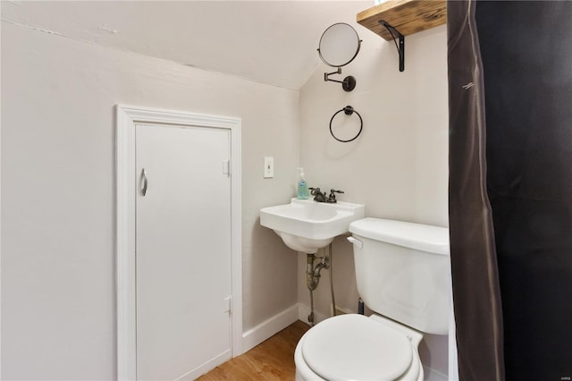 bathroom featuring baseboards, lofted ceiling, toilet, and wood finished floors