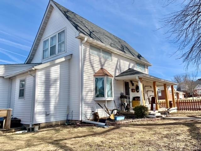 view of front of house with a porch, a front yard, and fence