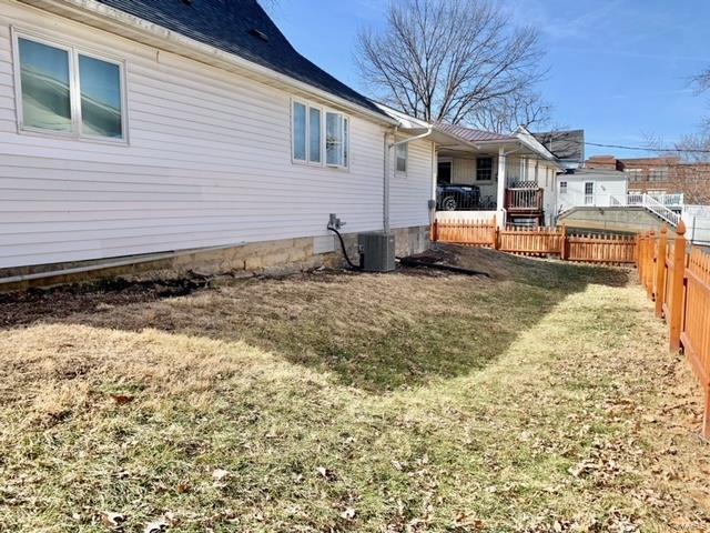 exterior space featuring a fenced backyard, a lawn, and central AC