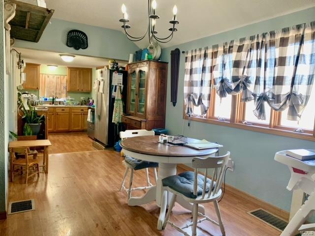 dining area featuring light wood-style floors, visible vents, and a notable chandelier