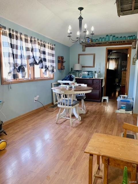 dining room featuring baseboards, visible vents, lofted ceiling, light wood-style floors, and a notable chandelier