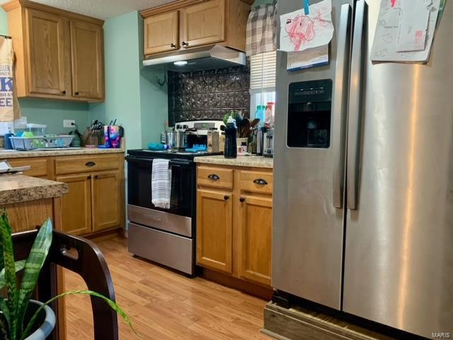 kitchen featuring stainless steel appliances, light wood-type flooring, and under cabinet range hood